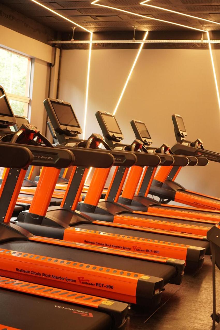 Fileira de esteiras Realleader RCT-900 laranja sob iluminação em LED na Arms Trainning