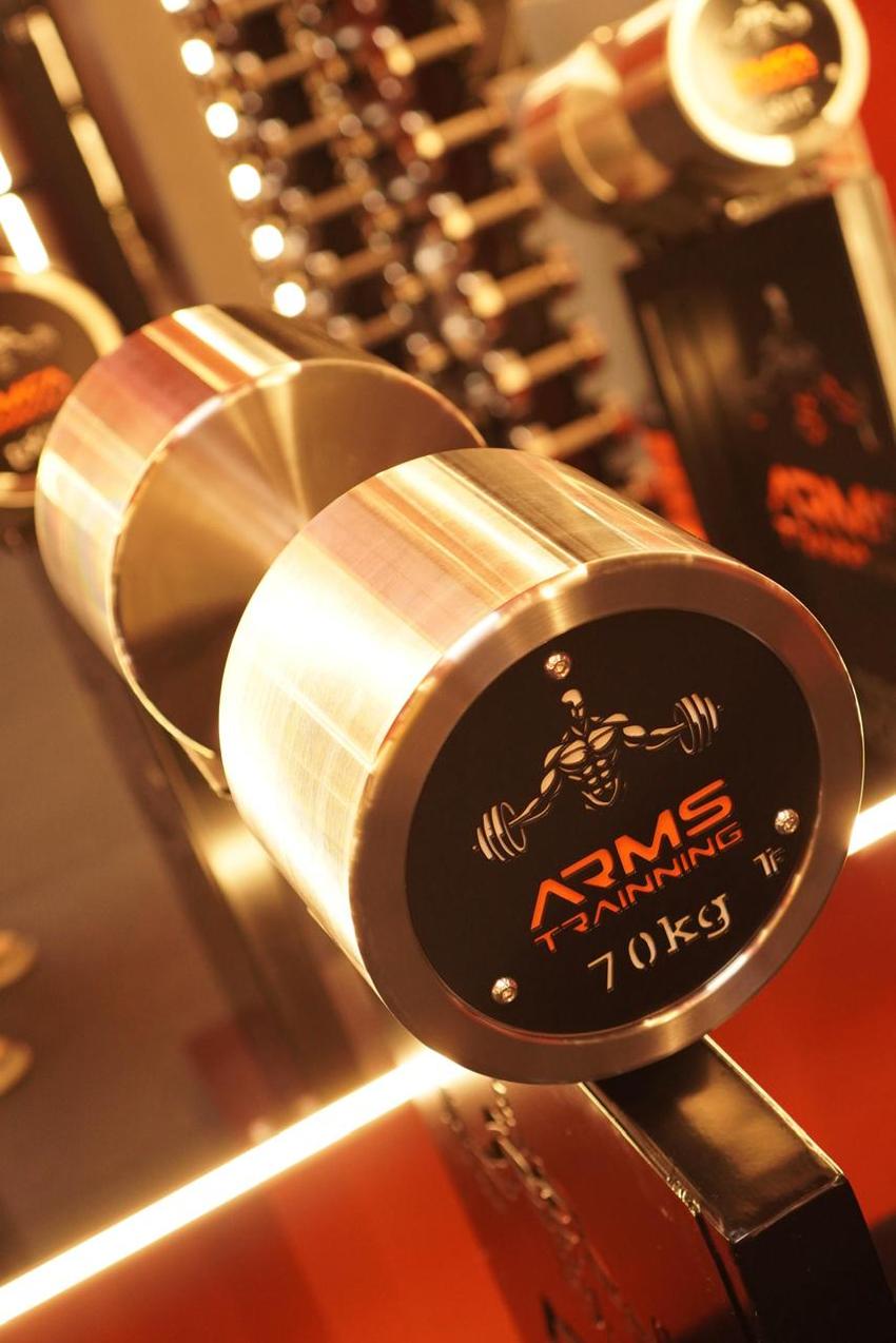 Close de um halter cromado de 70 kg com o logotipo Arms Trainning gravado na face